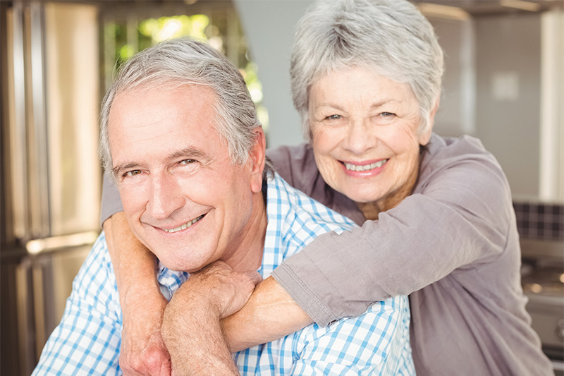 senior woman wrapping her arms around her husband